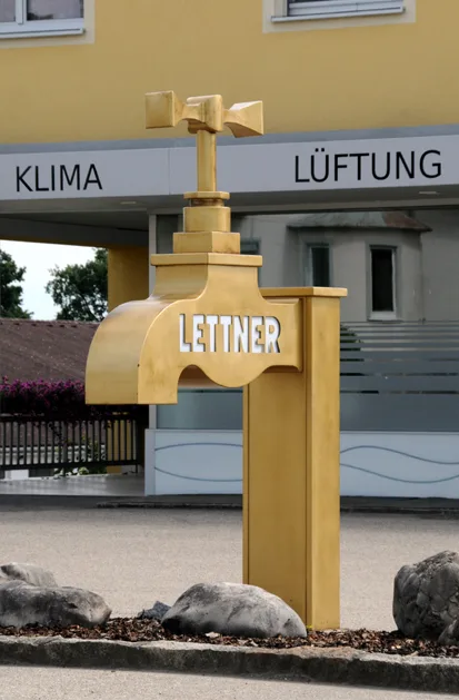 Der goldene Wasserhahn vor dem Gebäude mit der Aufschrift Klima und Lüftung